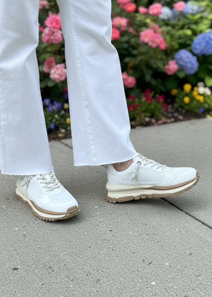 White sneakers on the sidewalk with flowers in the background