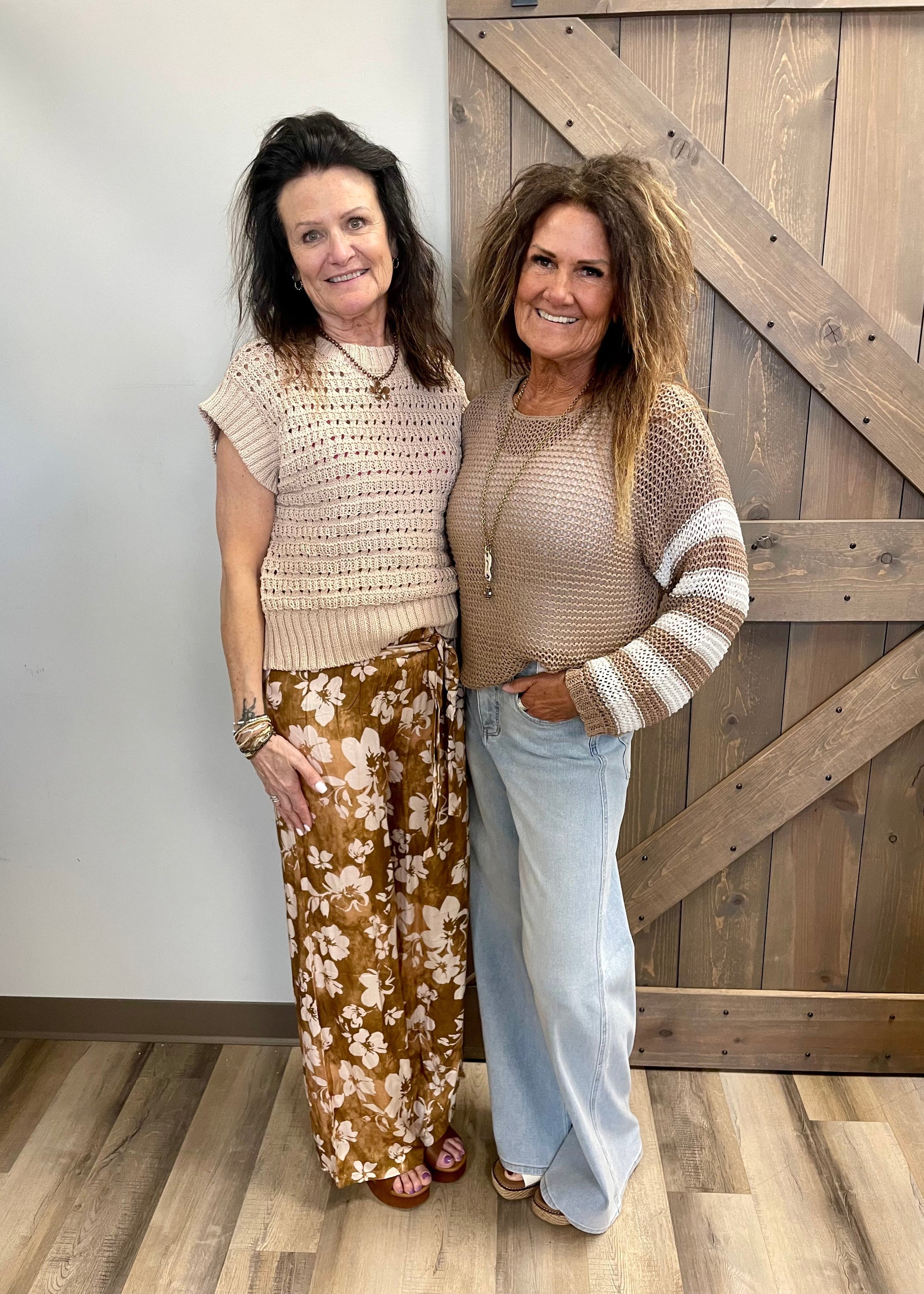 Two women standing side by side in front of a wooden door.