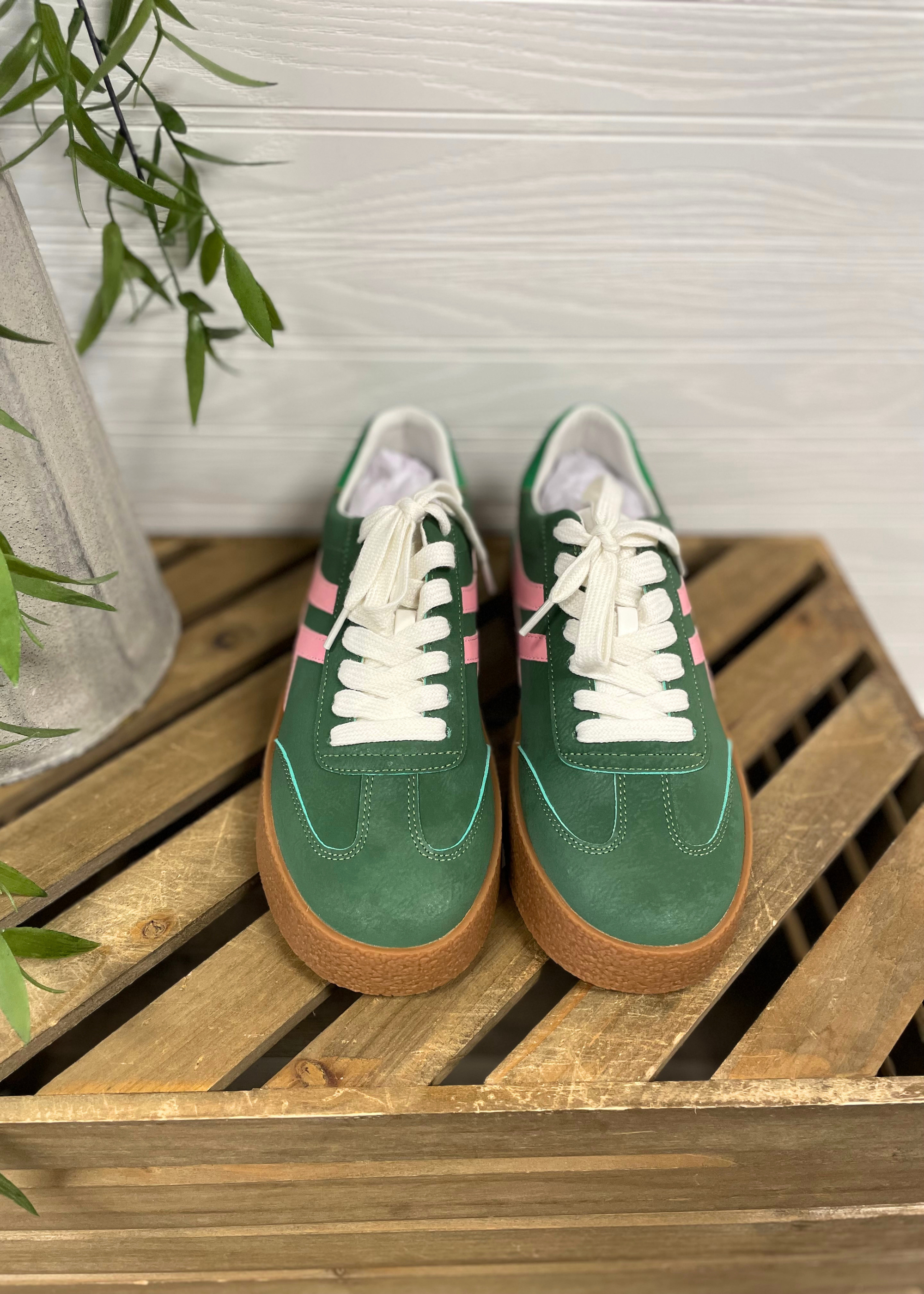 Green sneakers with white laces on a wooden crate against a light background